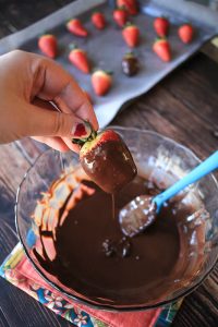 dipping a strawberry into melted chocolate