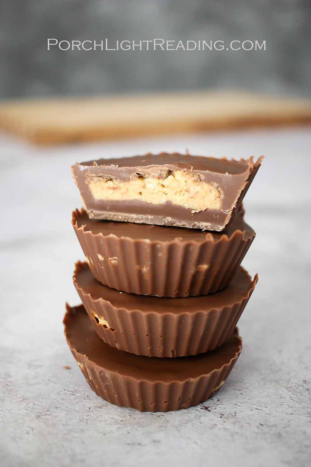 Four homemade peanut butter cups stacked on top of each other with the top one cut in half to show the peanut butter center.