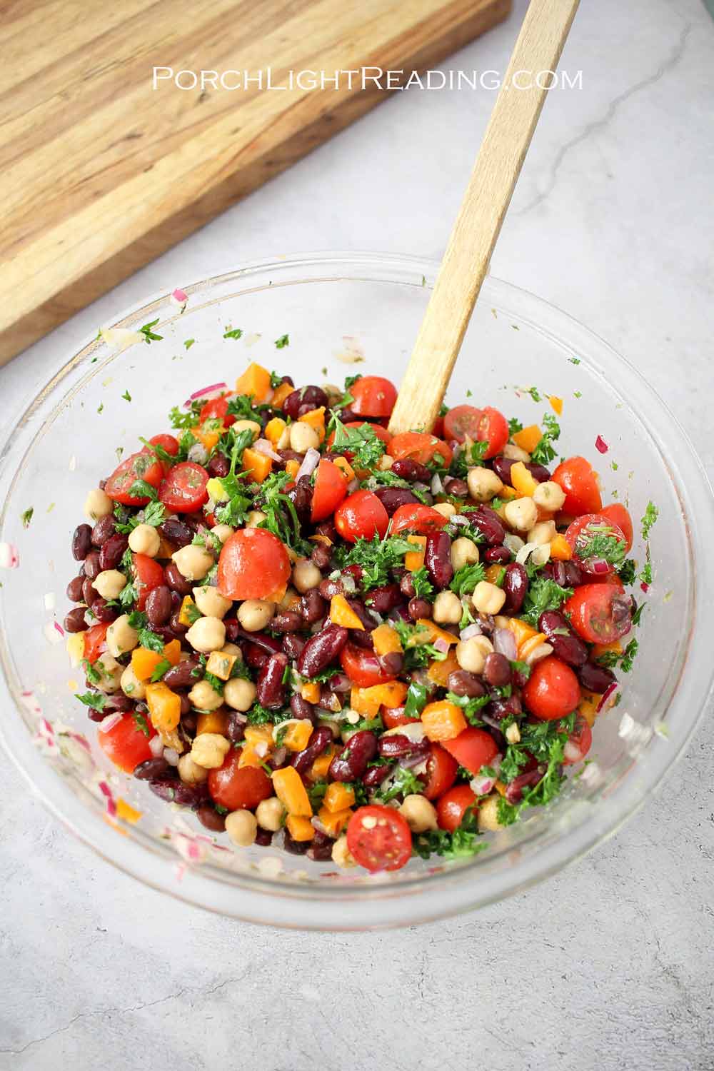 Brightly colored three bean salad in a glass bowl.