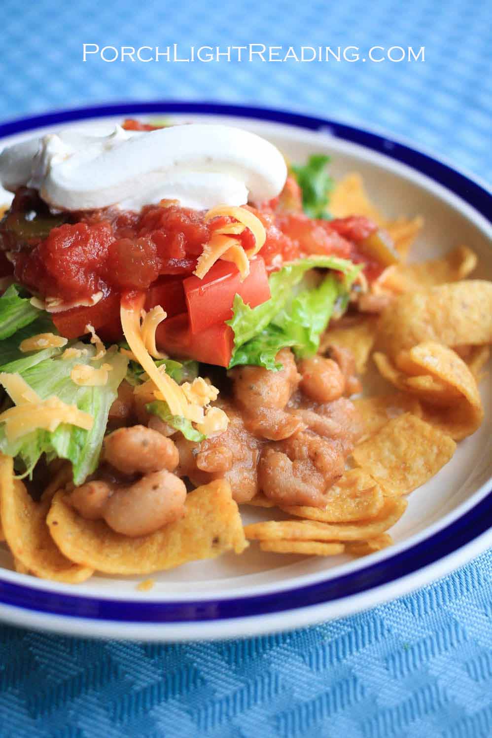 Haystacks dinner with Fritos as a base, followed by beans, cheese, lettuce, tomatoes, salsa and a dollop of sour cream.