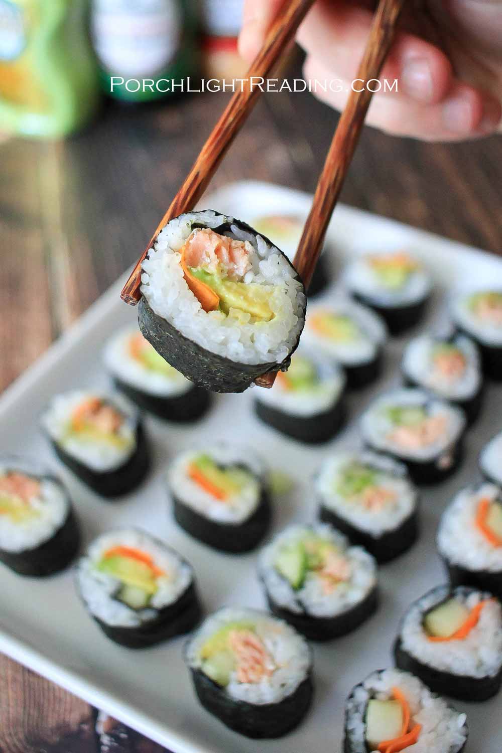 Sushi roll between chopsticks.
