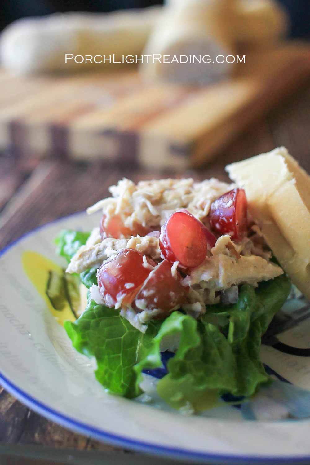 Chicken salad sandwich with sliced grapes on a bed of lettuce.