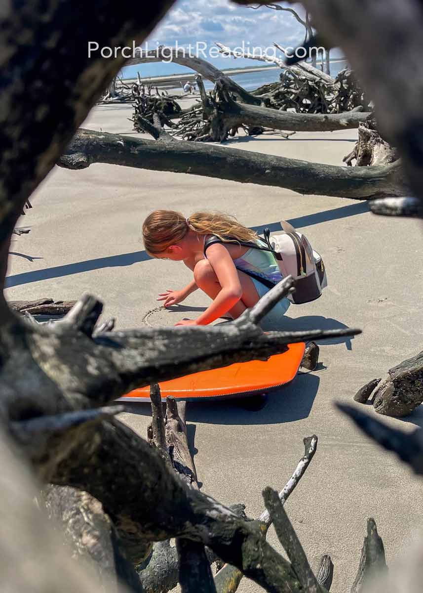 Little girl drawing in the sand. 