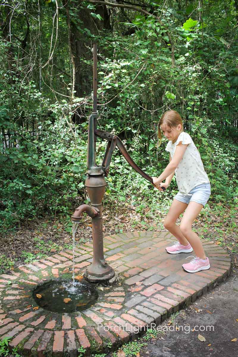 Little girl operating the old water pump.