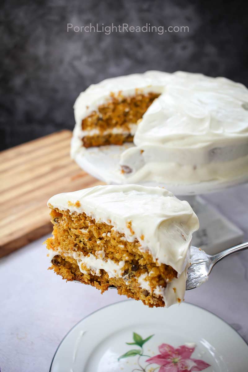 Slice of carrot cake about to be put on white plate.