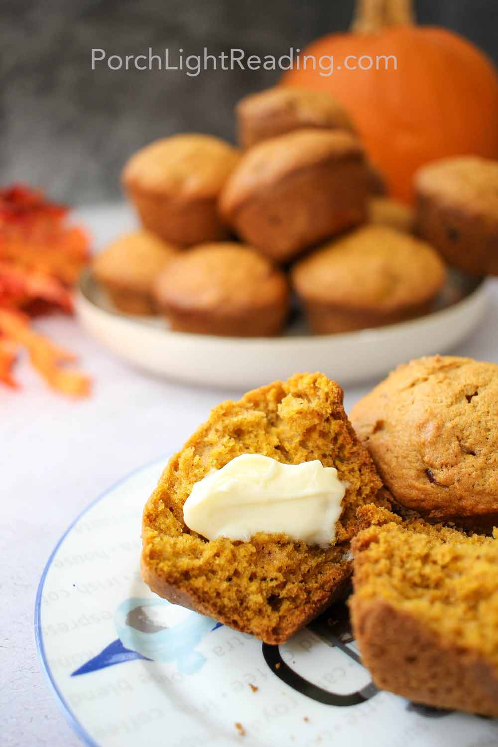 Moist pumpkin muffin split in half with a bit of butter melting in the center.
