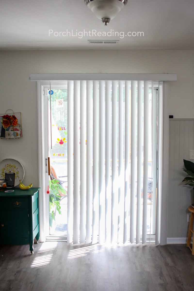 Broken track blinds in front of glass sliding door. 