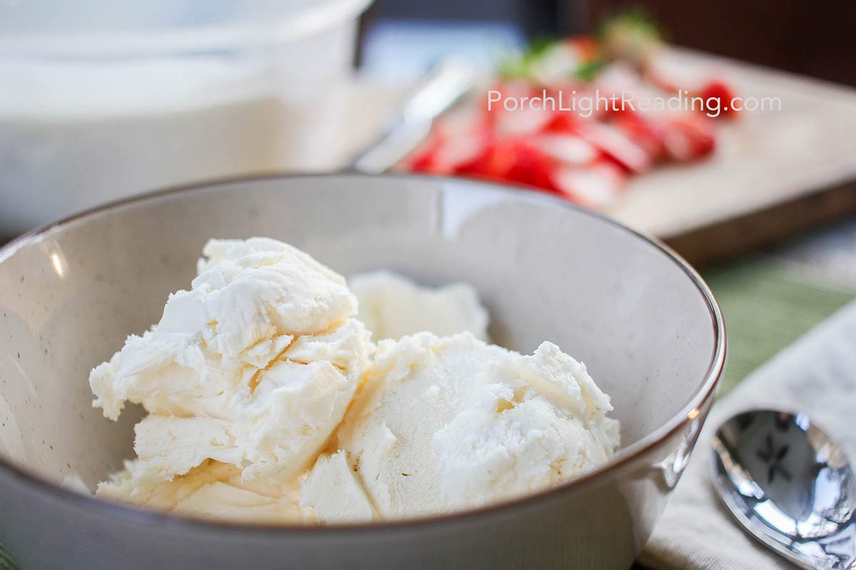 Creamy homemade vanilla ice cream with strawberries on a cutting board. 