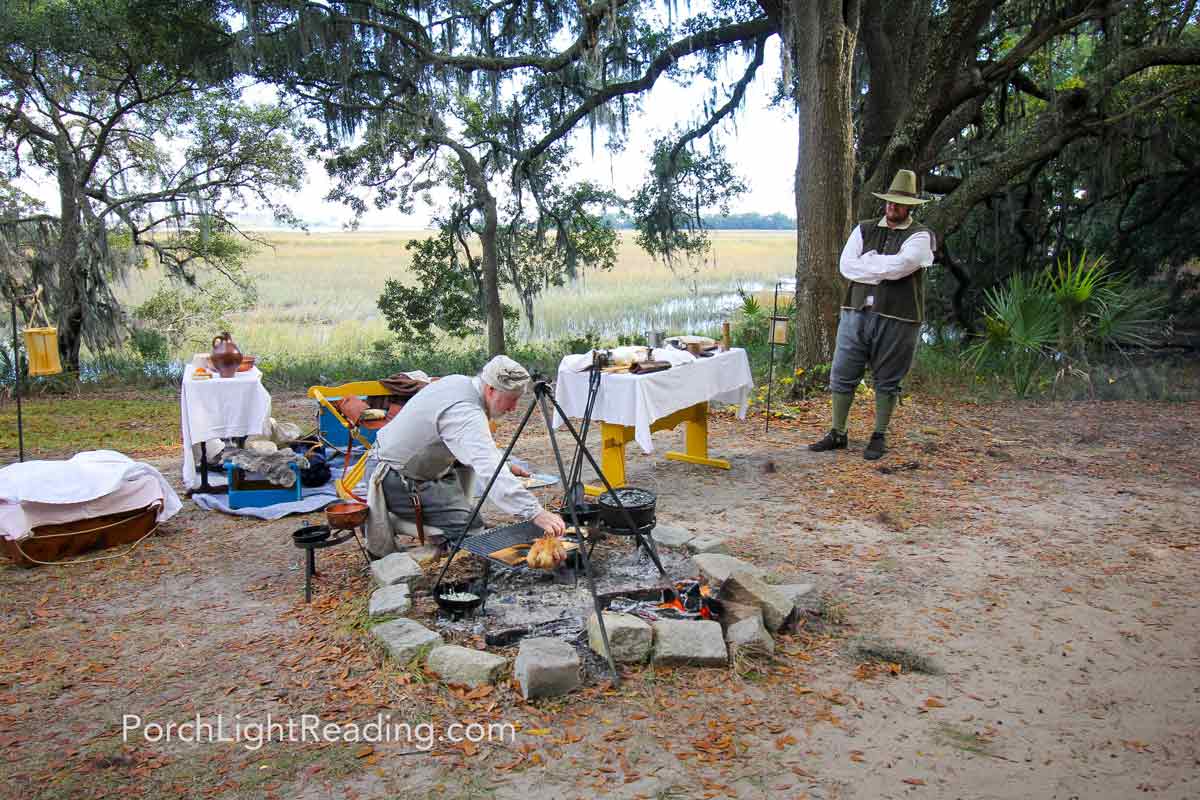 Actors portraying live in the early 1700's with century specific clothing and cooking over an open fire.