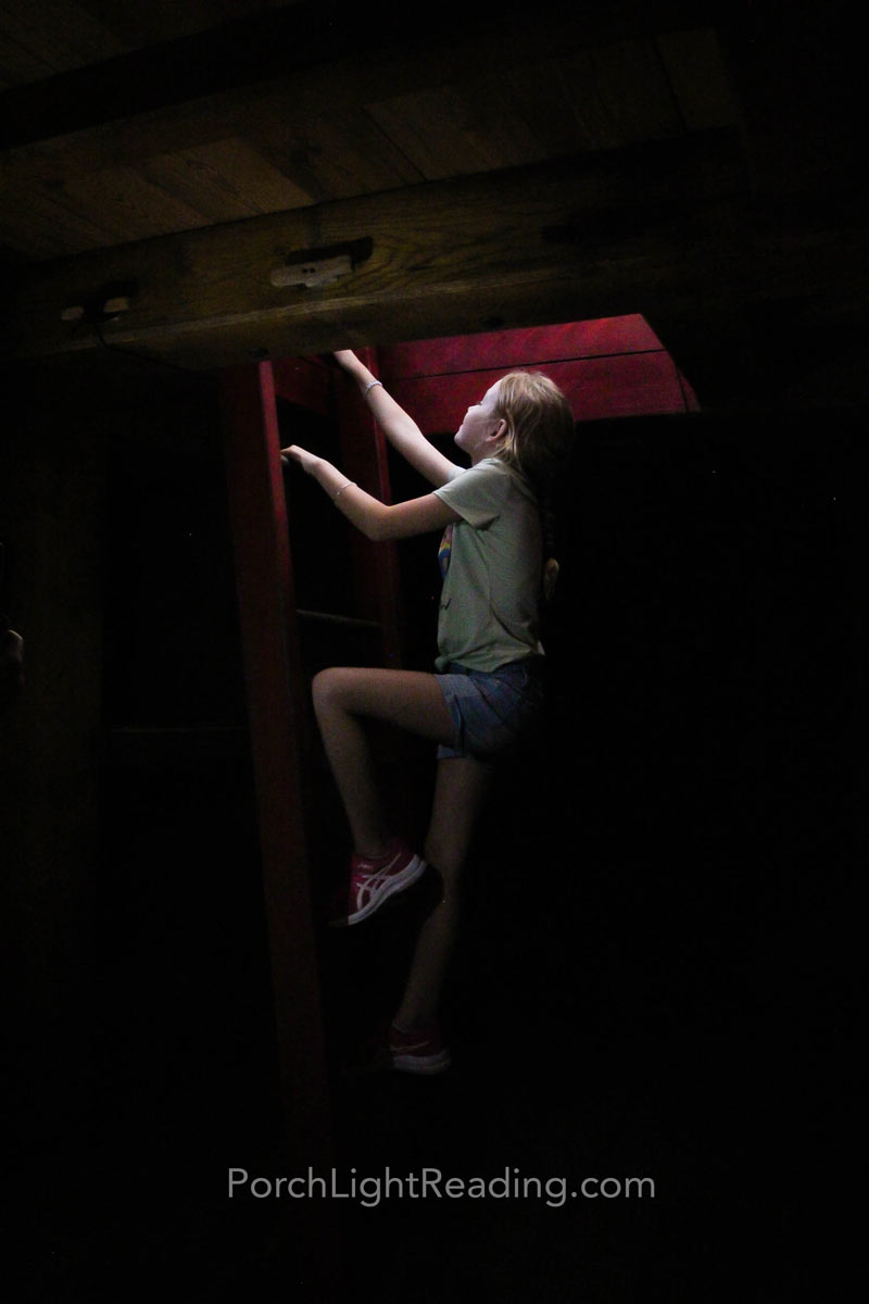Little girl climbing up the latter in the hull of the ship.