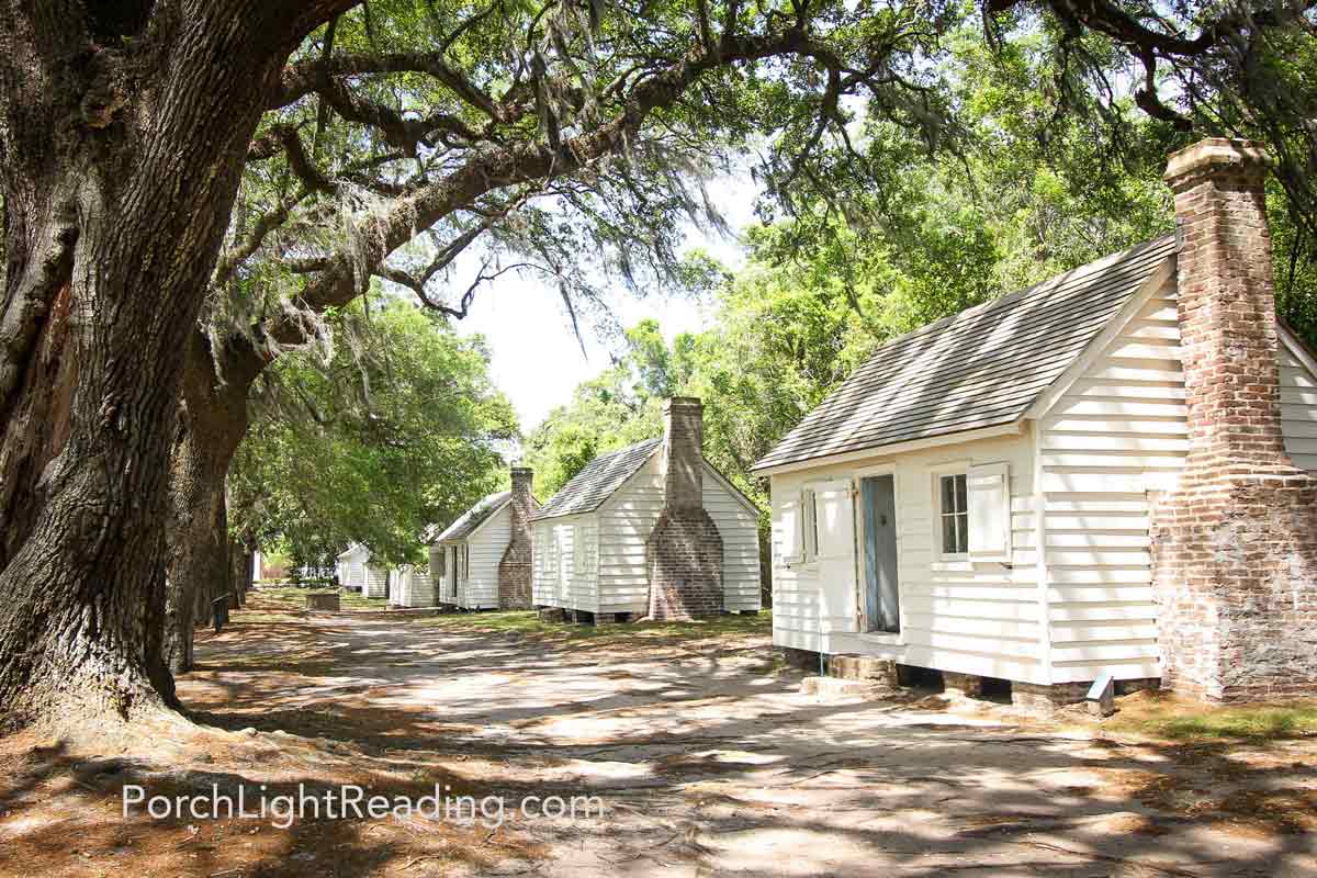Slave cabins under large oak tree branches.