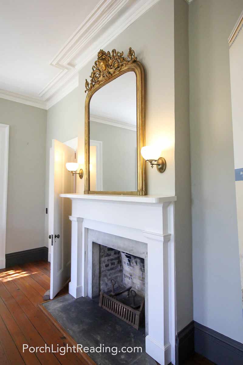 Large white fireplace with golden mirror over the hearth.