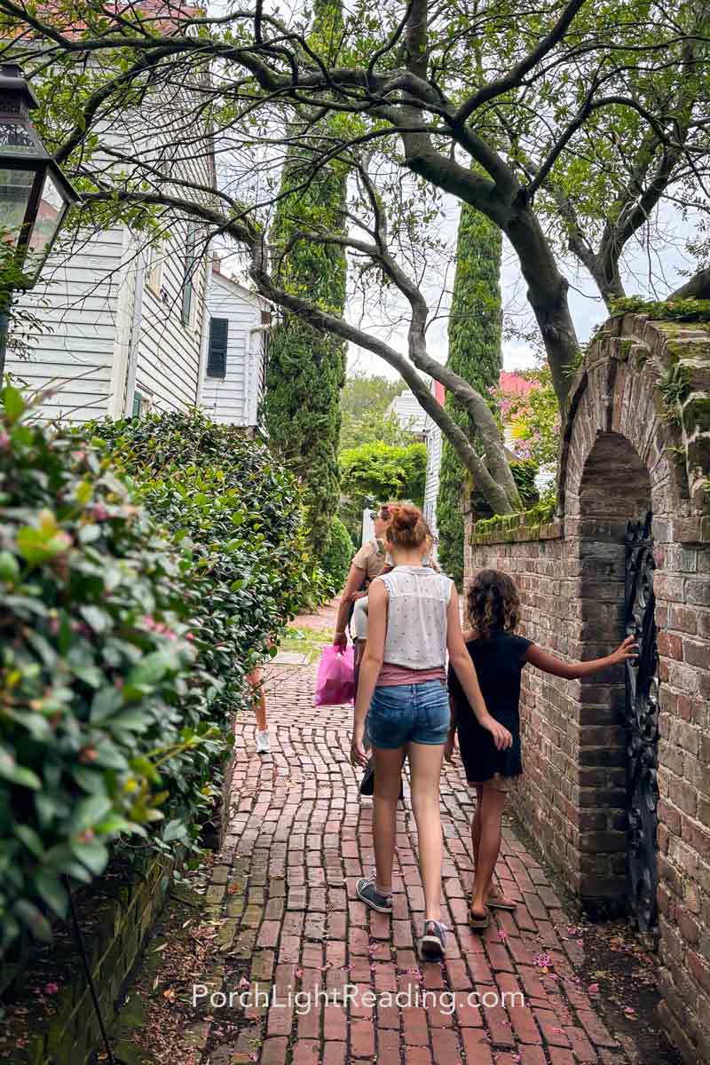 Family strolling along Stoll's Alley with a red brick pathway and hidden gardens. 