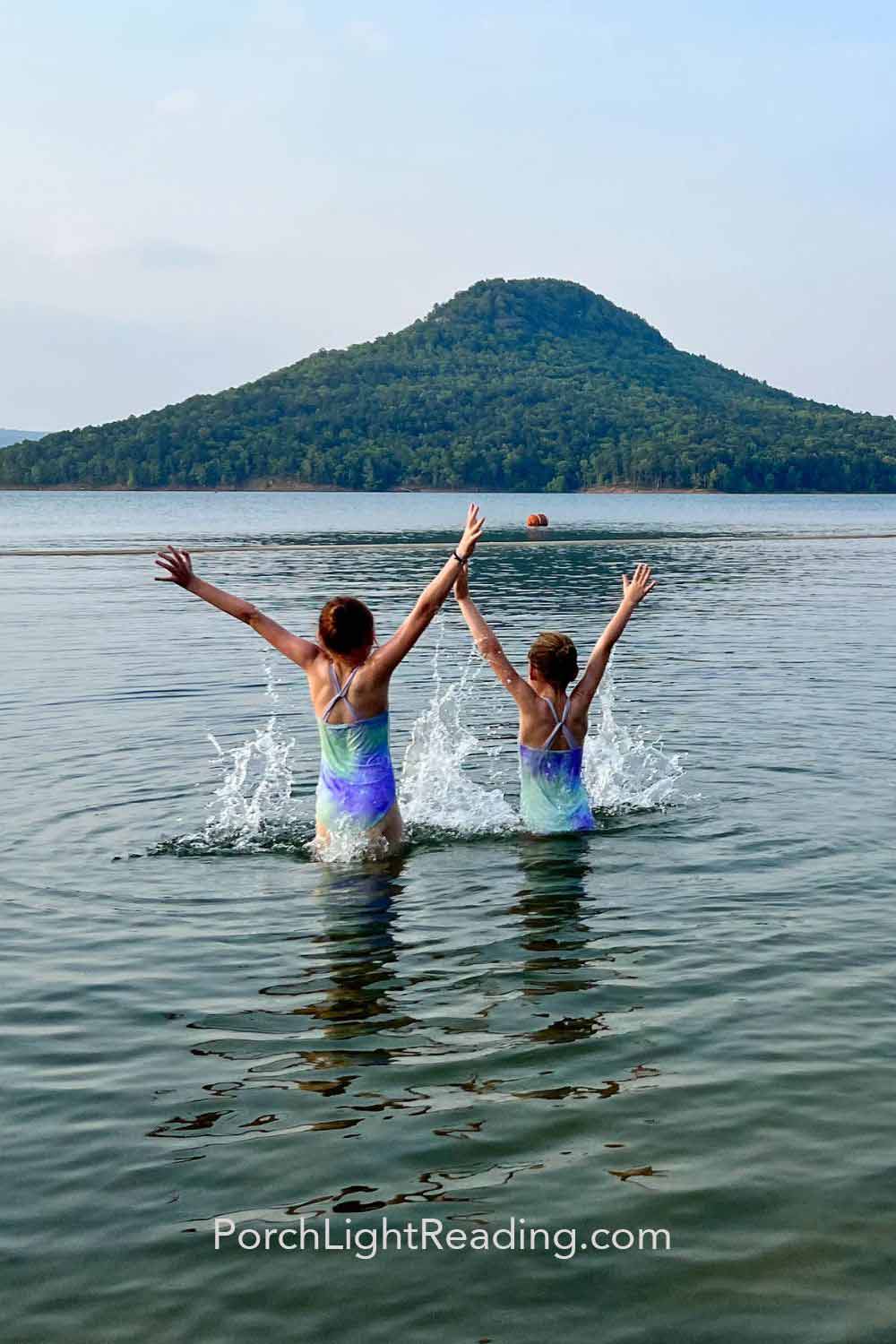 Kids jumping out of the water and splashing around. 
