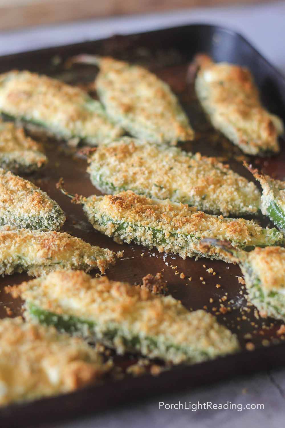 Oven baked jalapeño poppers on a baking sheet with a panko topping. 