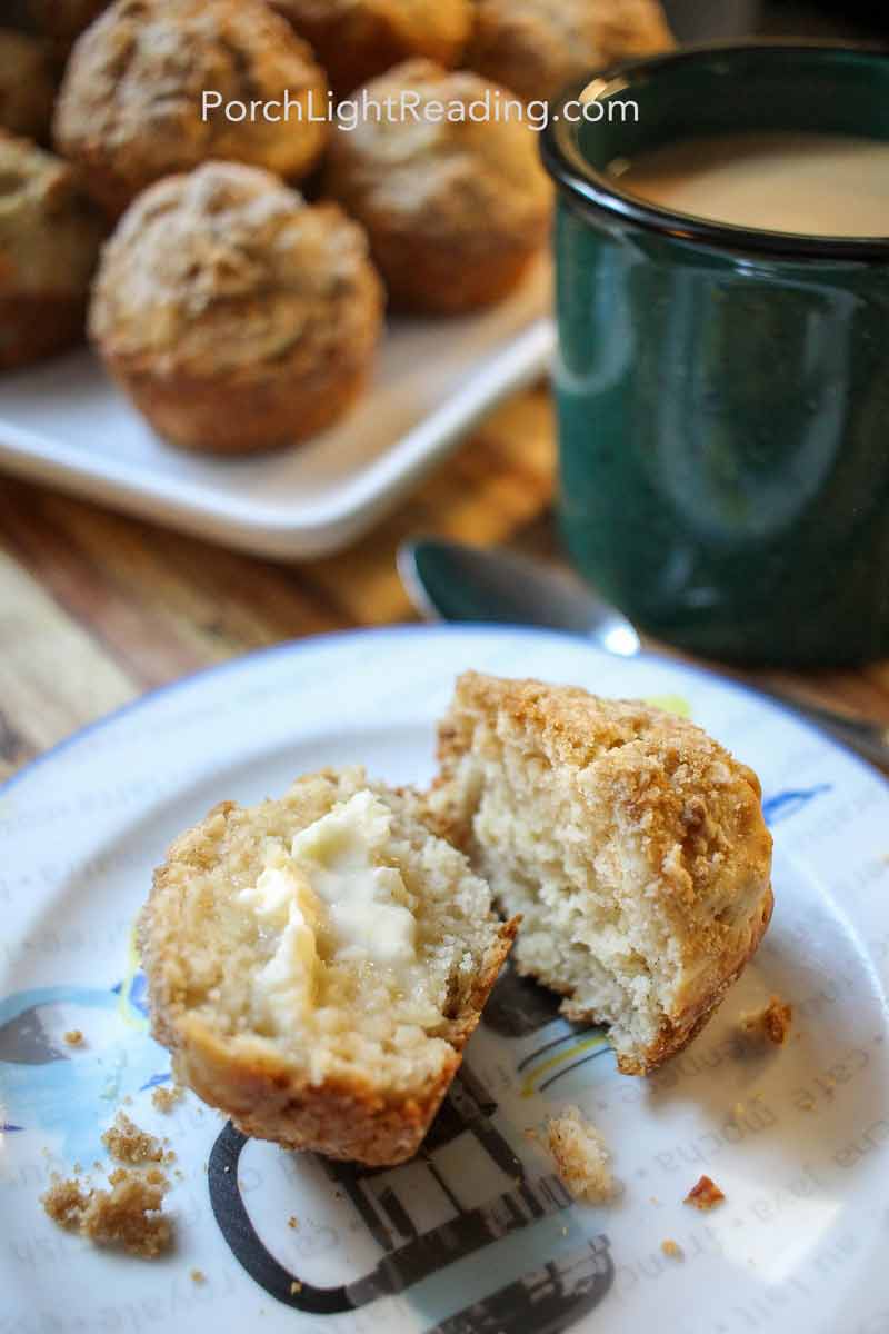 Homemade apple cinnamon muffins on a plate with butter and a cup of coffee. 