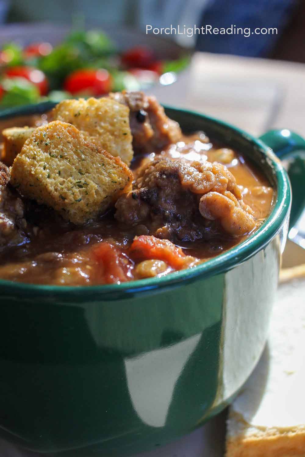 Bowl of hearty lentil meatball soup with bread on the side. 