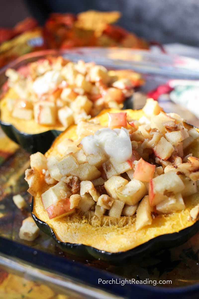 Baked acorn squash stuffed with apples and brown sugar in a clear baking dish. 