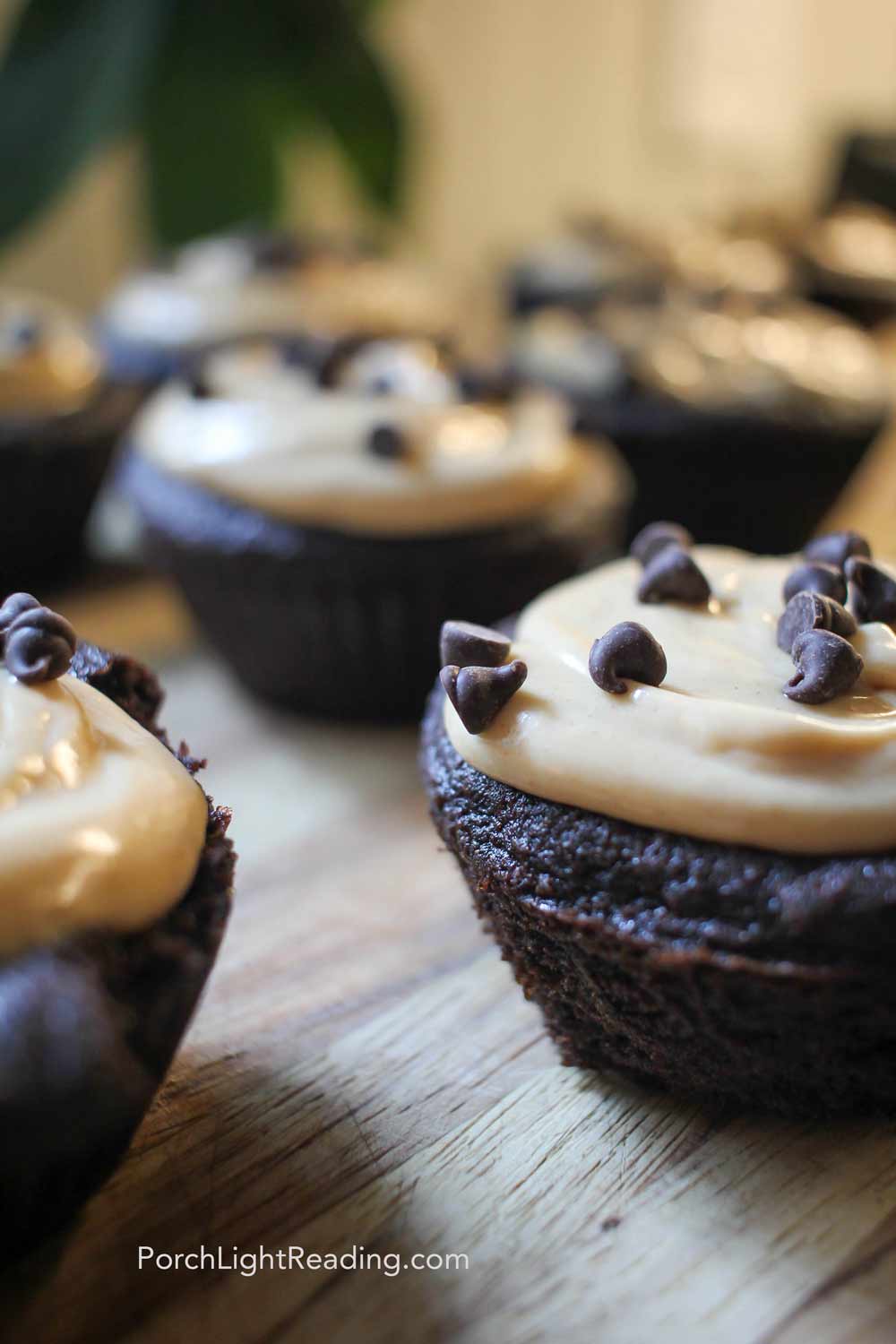 Black bean cupcakes on a wooden cutting board with peanut butter frosting. 
