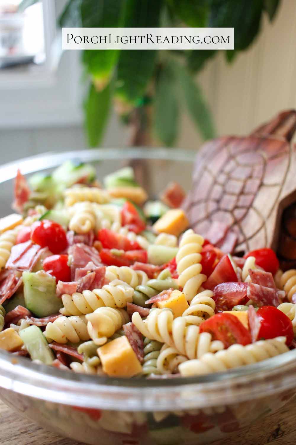 Pasta salad with fresh veggies in a clear serving bowl. 