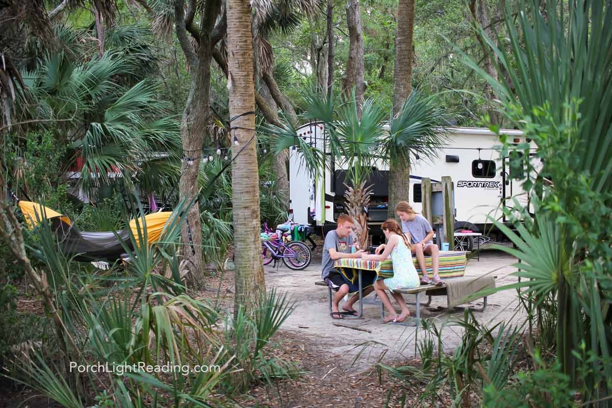 Family at the Edisto Beach State Park campground. Sitting at the picnic table with string lights and a yellow hammock. 