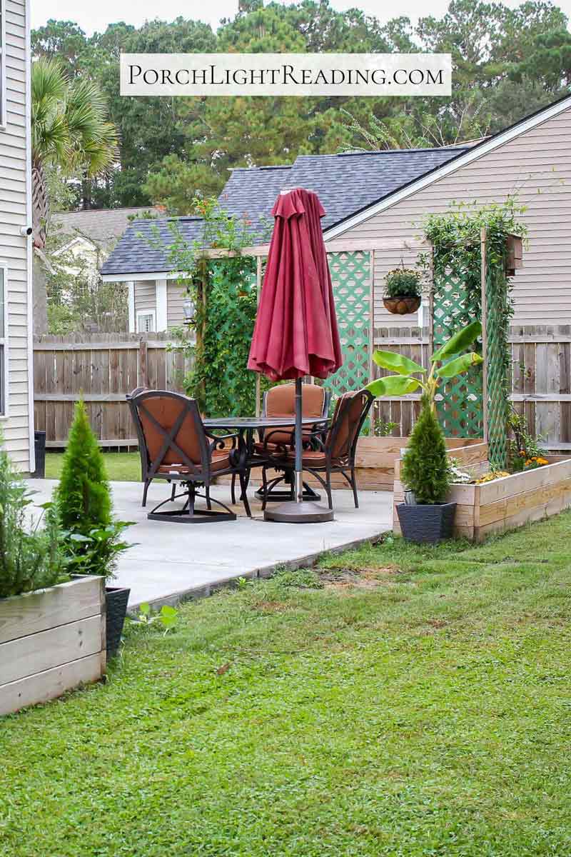 Concrete slab patio surrounded by raised garden beds with mud as you step into the grass. 