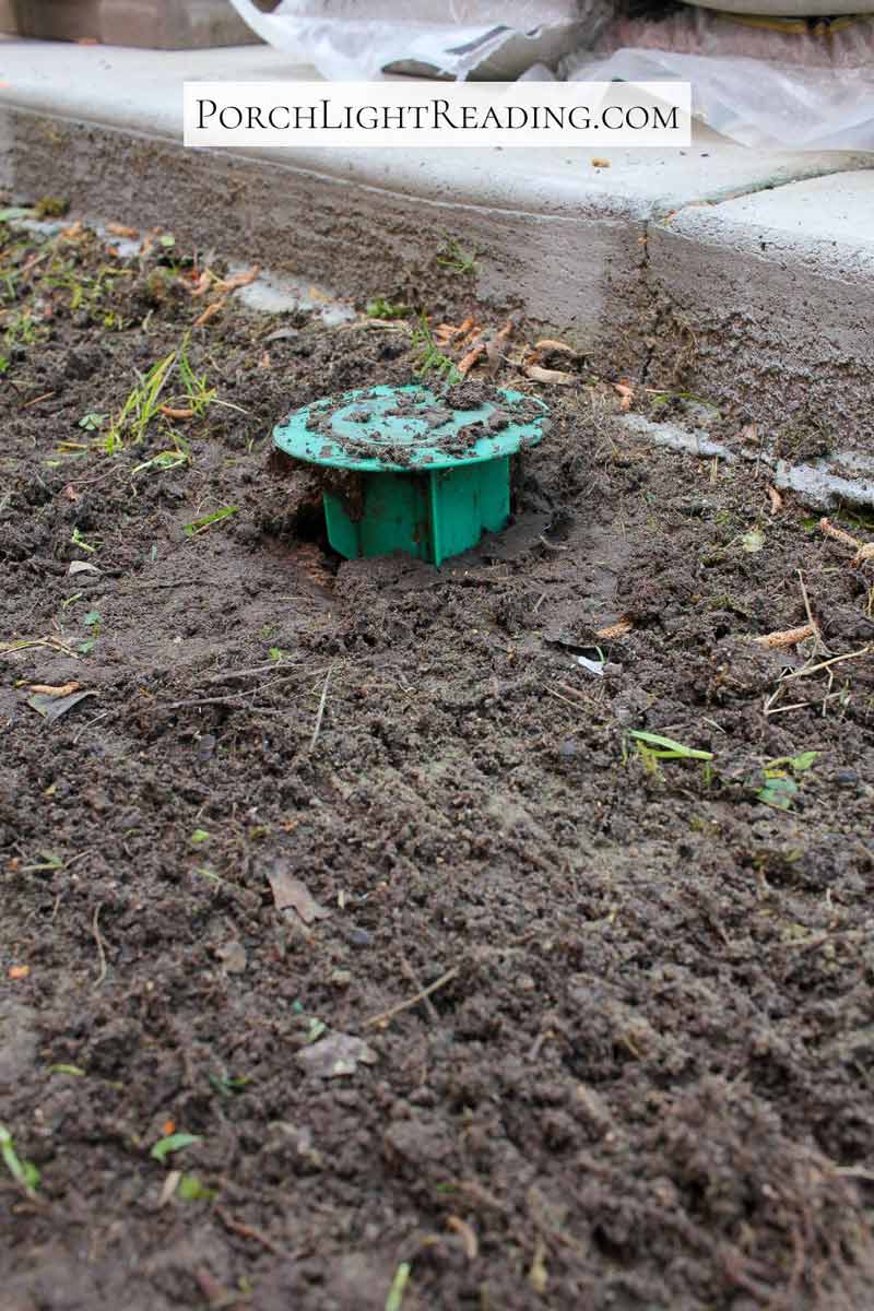 Raising a termite bait trap before installing pavers. 