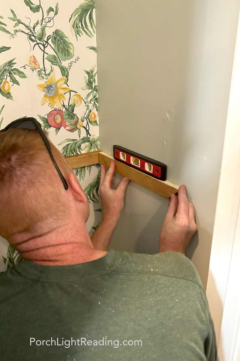 Securing the supports to the pantry walls and making sure they are level. 