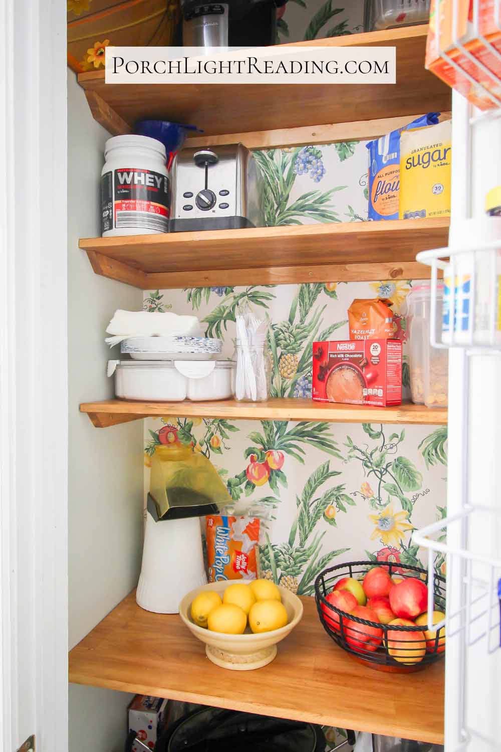 Beautiful wooden pantry shelves with tropical wallpaper. 
