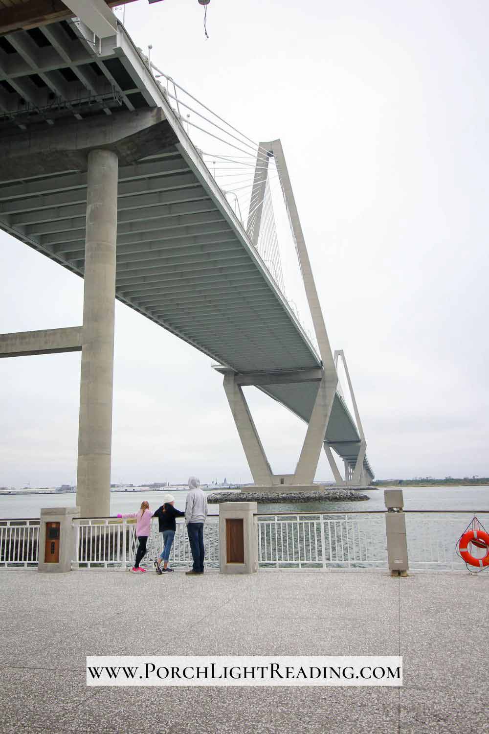 Dad with two kids at the end of the Mount Pleasant Pier with tall bridge over them. 