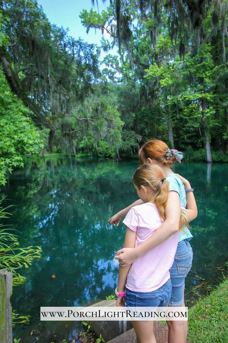 Beautiful blue pond with two girls looking out over the water. 