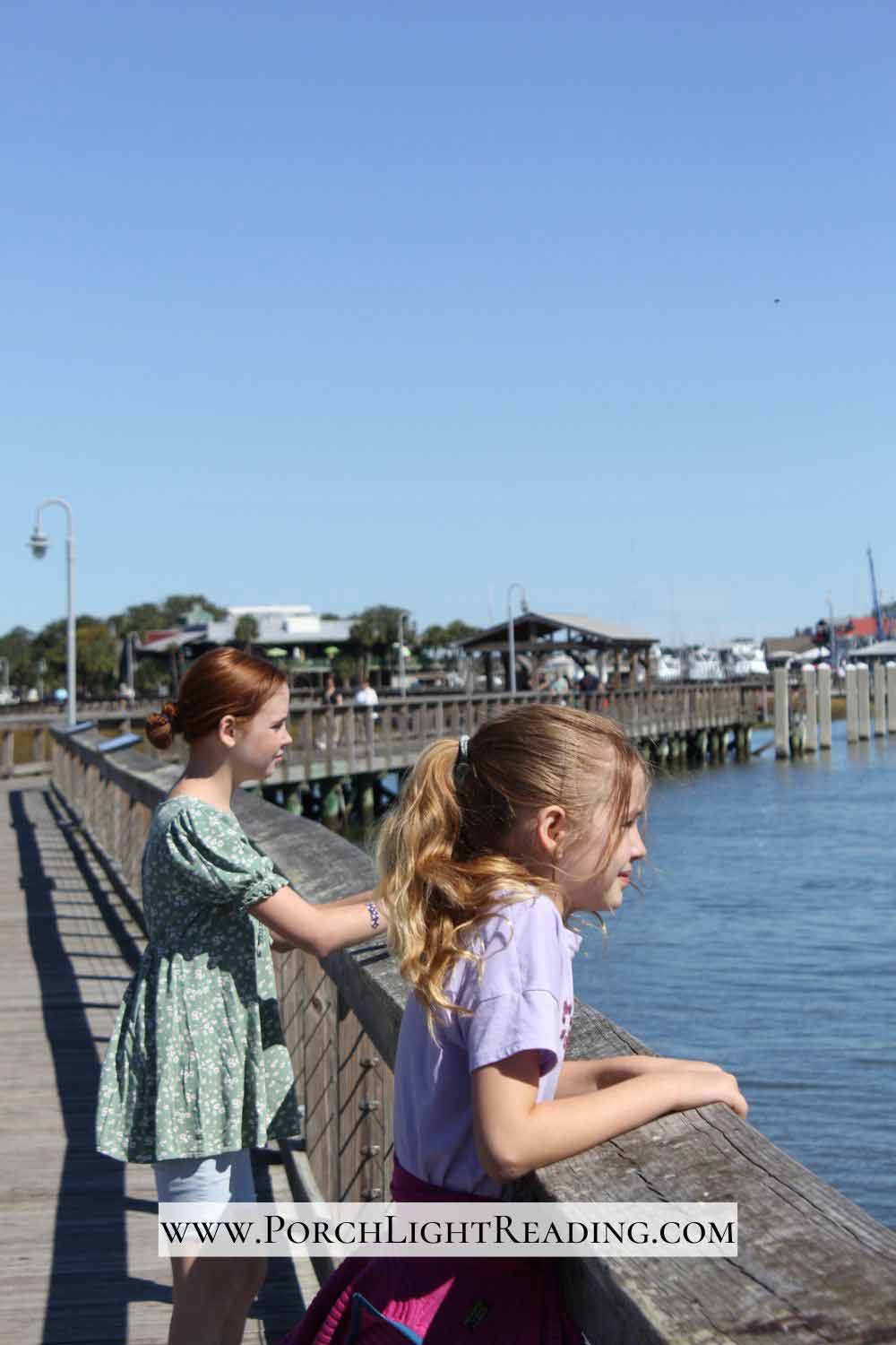 Two kids looking out over the water at Shem Creek Boardwalk. 