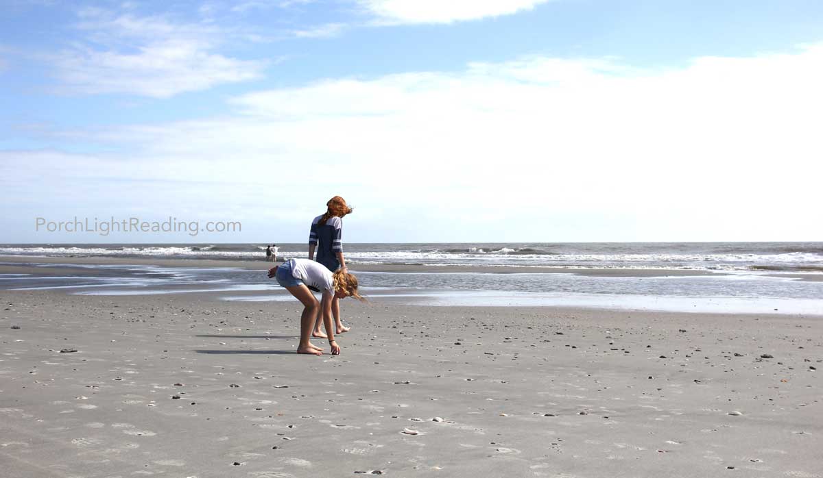 Two kids looking at sea shells along the sand at Folly Beach. 