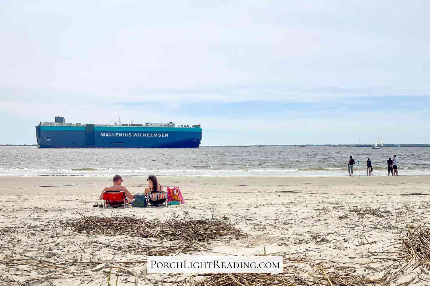 Couple enjoying the beach along Sullivan's Island with a large cargo ship in the water. 