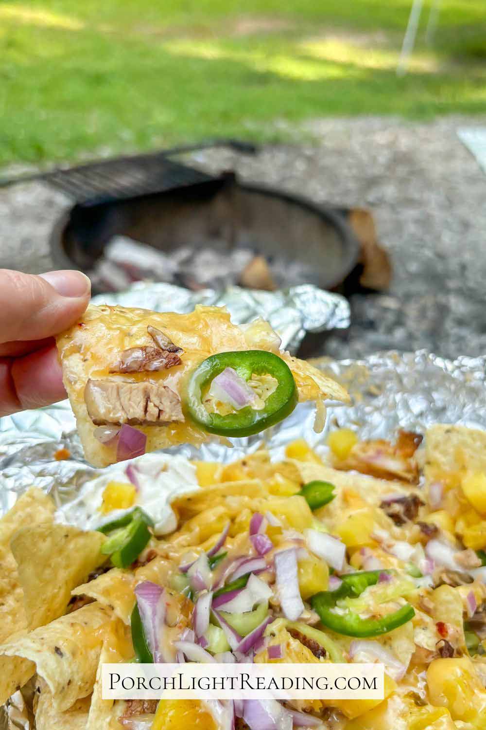Campfire nachos in a tin foil packet with jalapeno, onions, and meat.