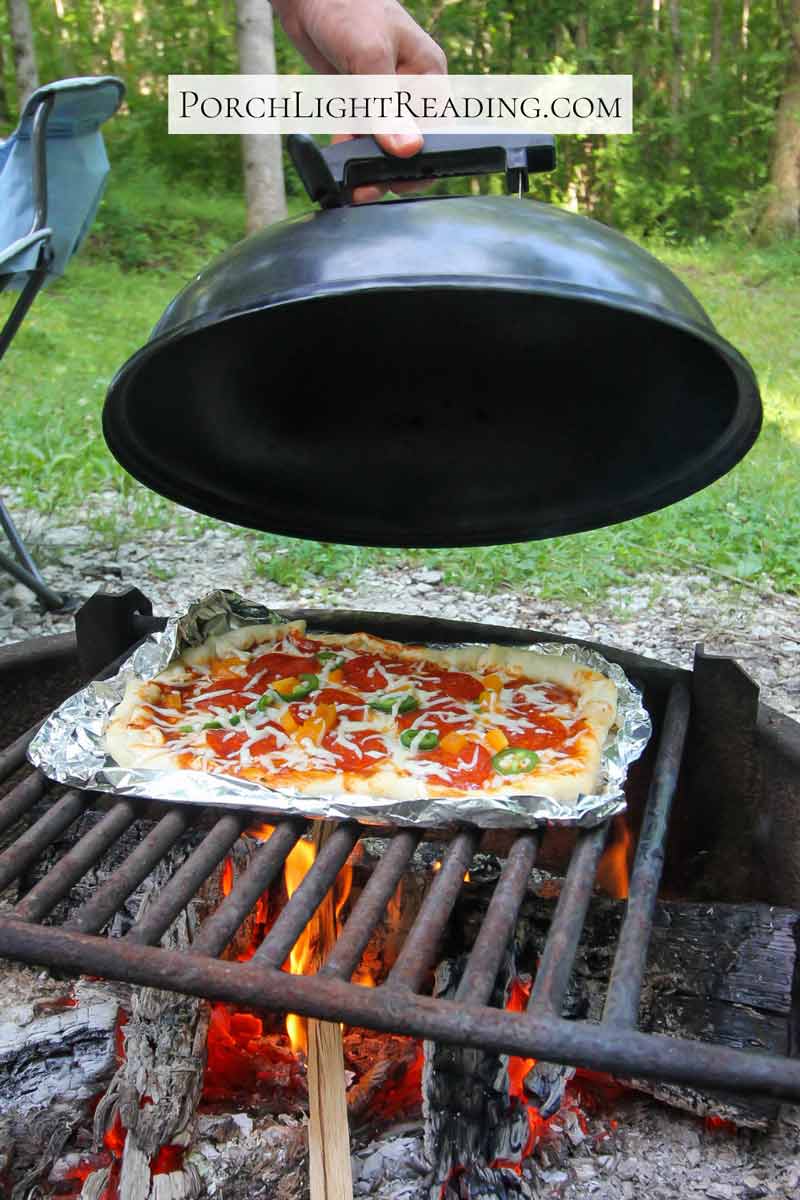 Removing the lid to show our almost done campfire pizza. 
