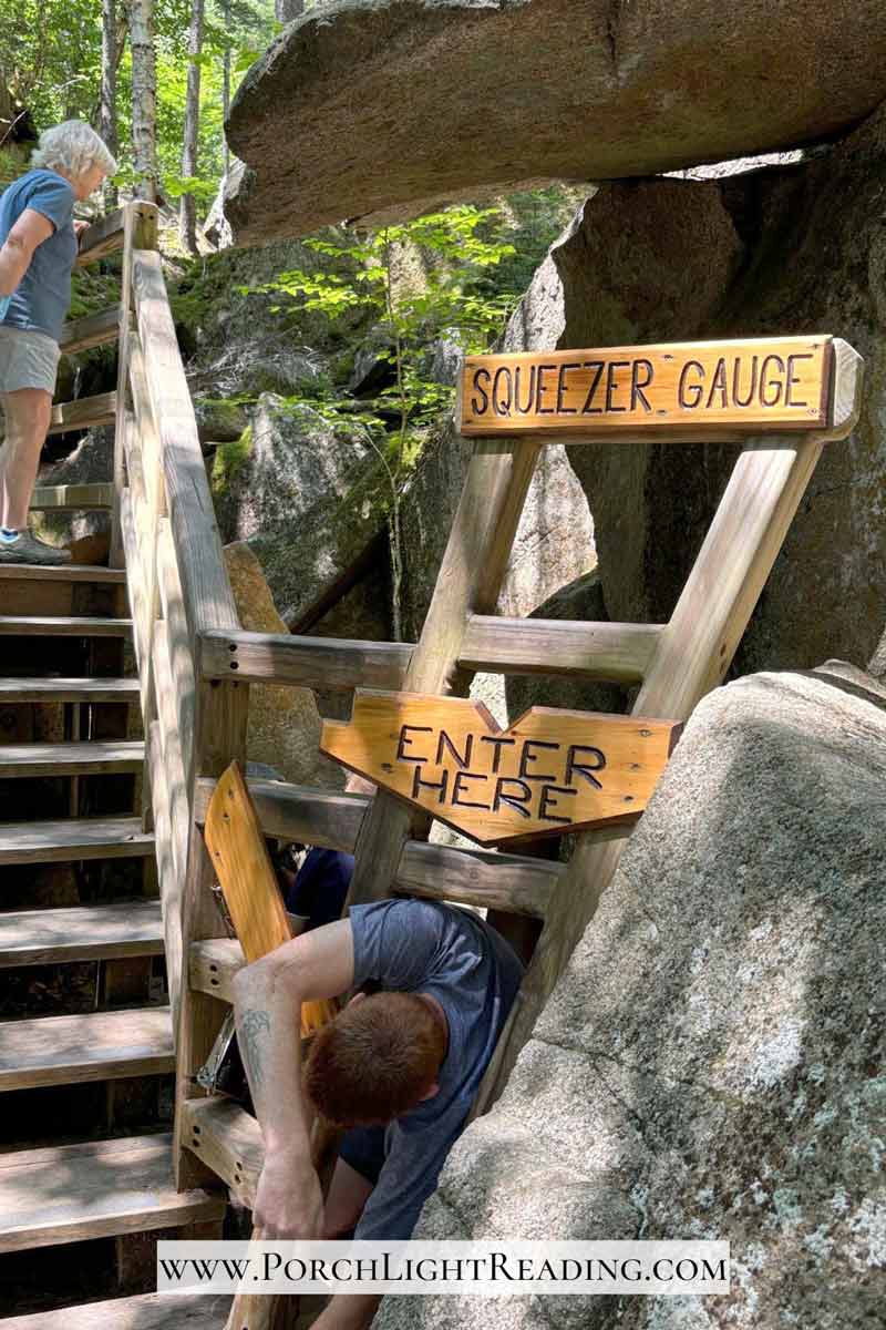 Adult going through a squeeze gauge to see if you will fit through the small cave.