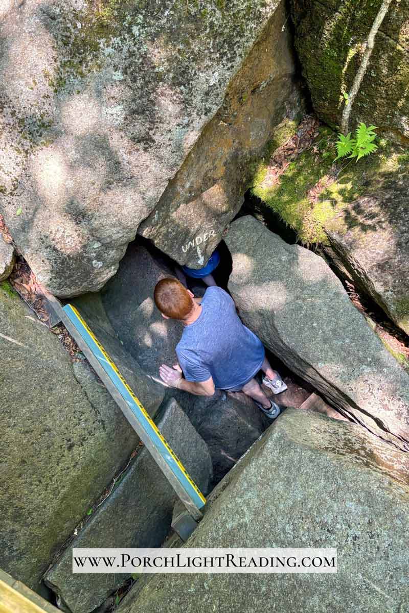 Squeezing under a rocking to get into the cave.