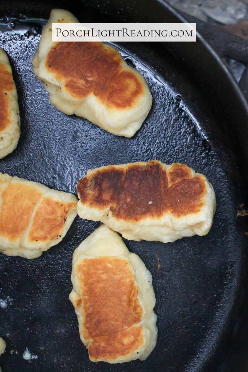 Golden Crescent rolls cooking over a campfire.