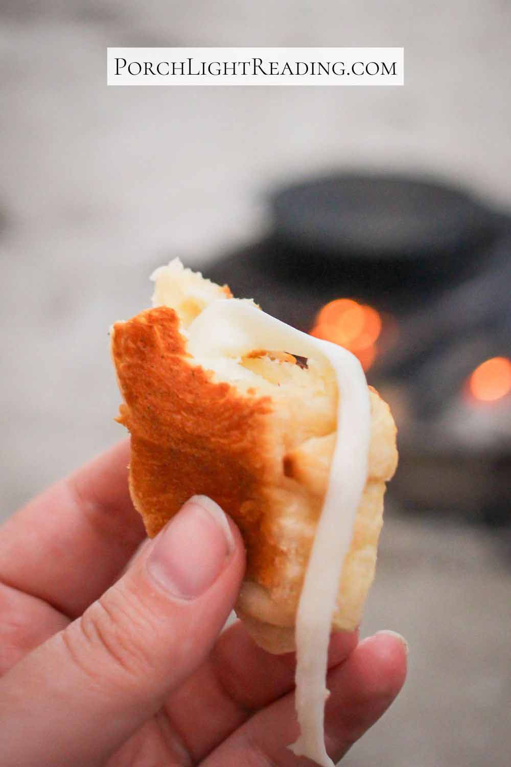 Mozzarella cheese oozing out of a crescent pizza roll.
