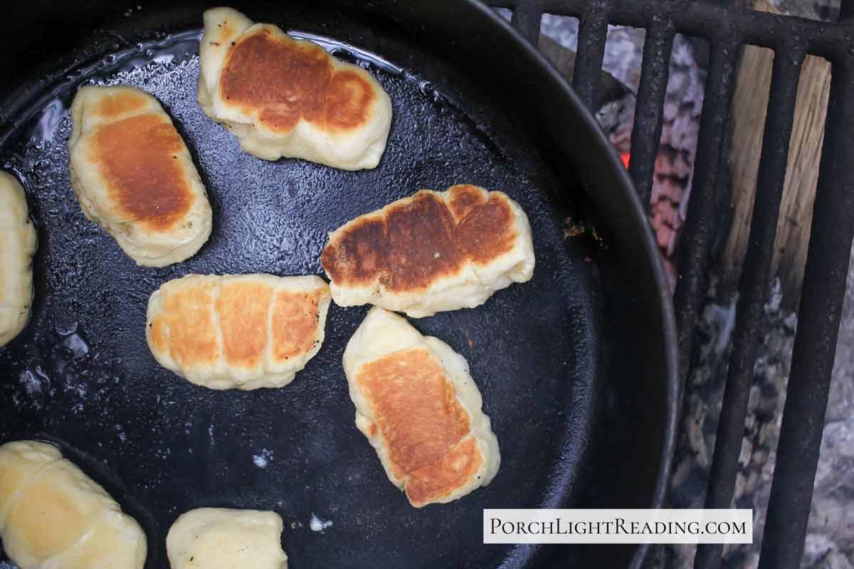Crescent rolls stuffed with mozzarella cheese cooking over a campfire.