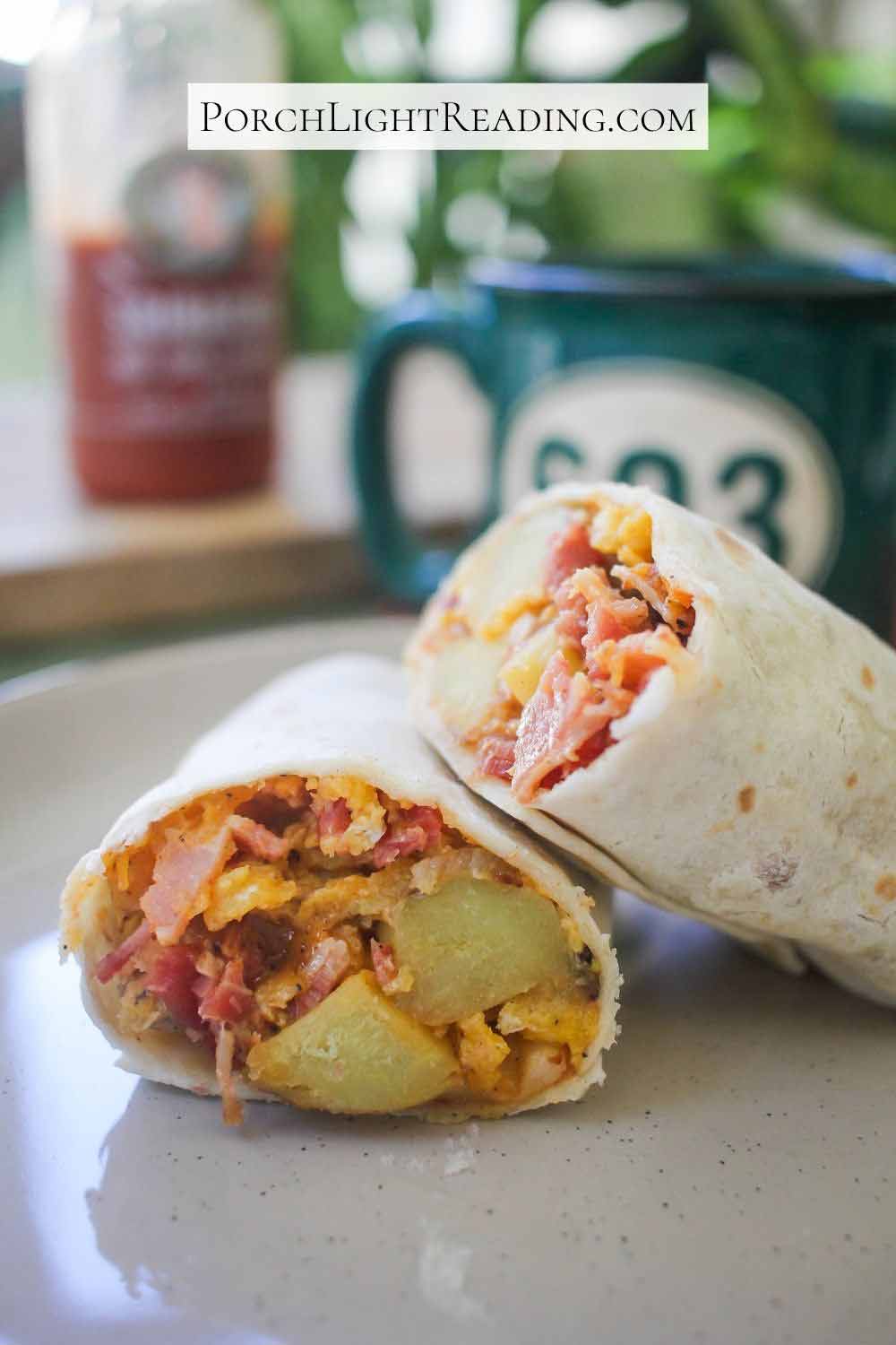 A hearty burrito cut in half on a tan plate. Served with coffee in a green mug.